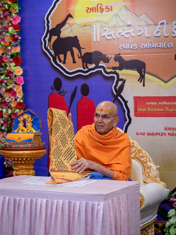 Swamishri spreads an upvastra over the list of winners to honor them