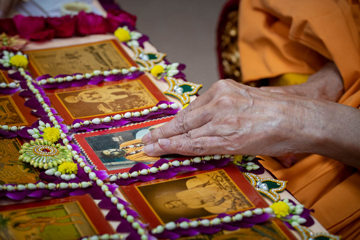 Swamishri adjusts a murti of Brahmaswarup Pramukh Swami Maharaj in his daily puja