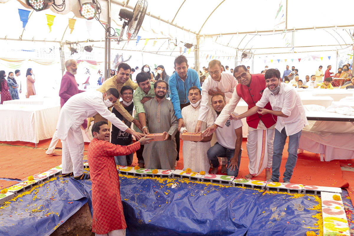 Devotees and well-wishers lay their bricks in the foundation pit