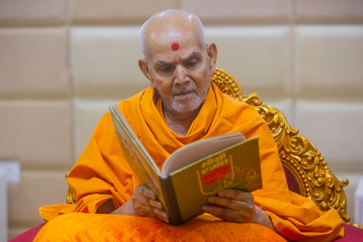 Swamishri reads a book 'Yogi Darshan'