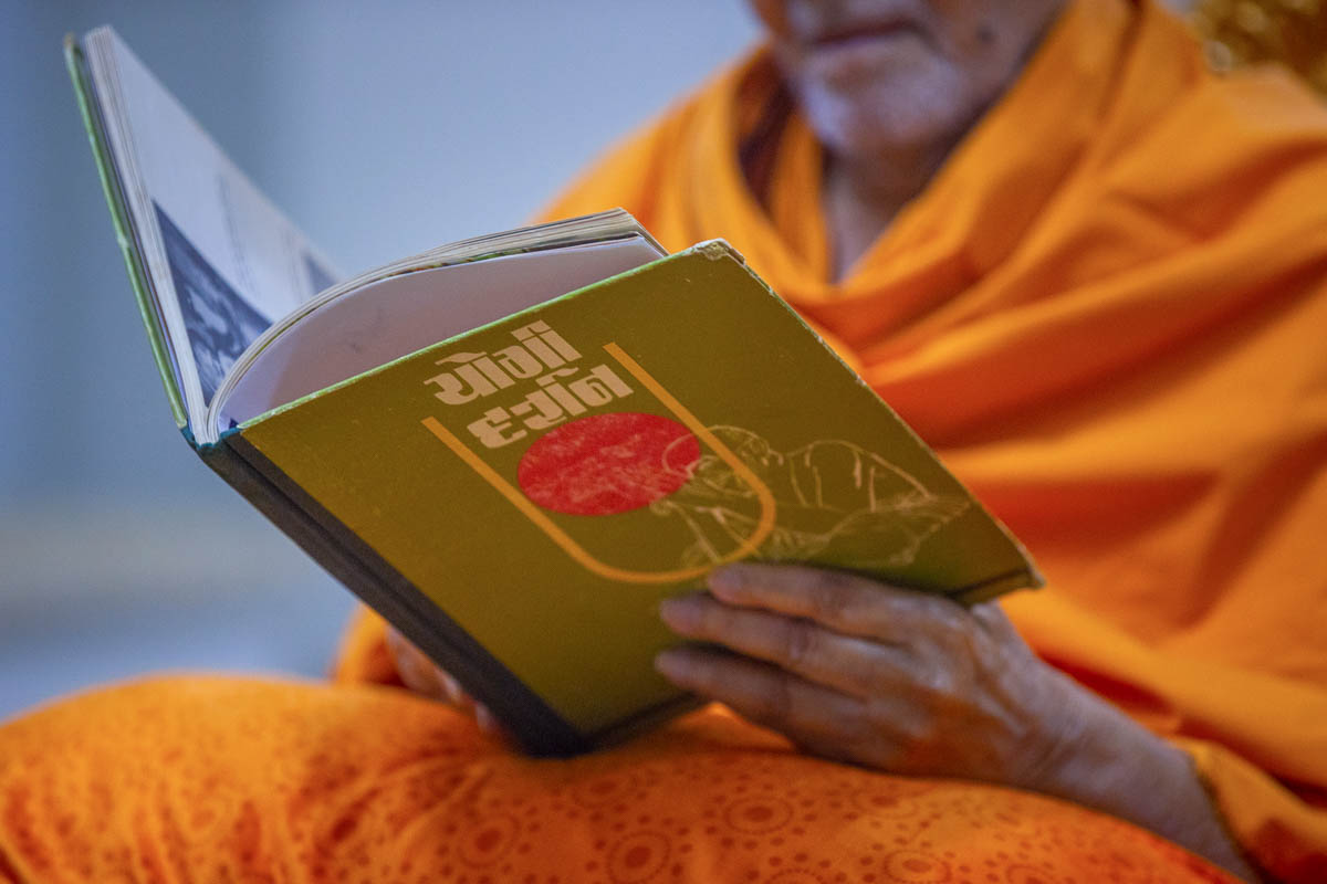 Swamishri reads a book 'Yogi Darshan'