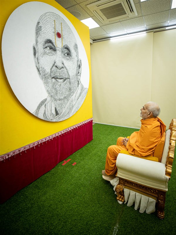 Swamishri observes an artwork of Pramukh Swami Maharaj