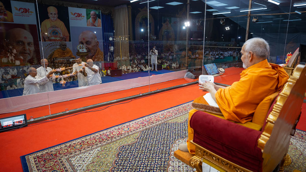 Devotees honor Swamishri with a garland