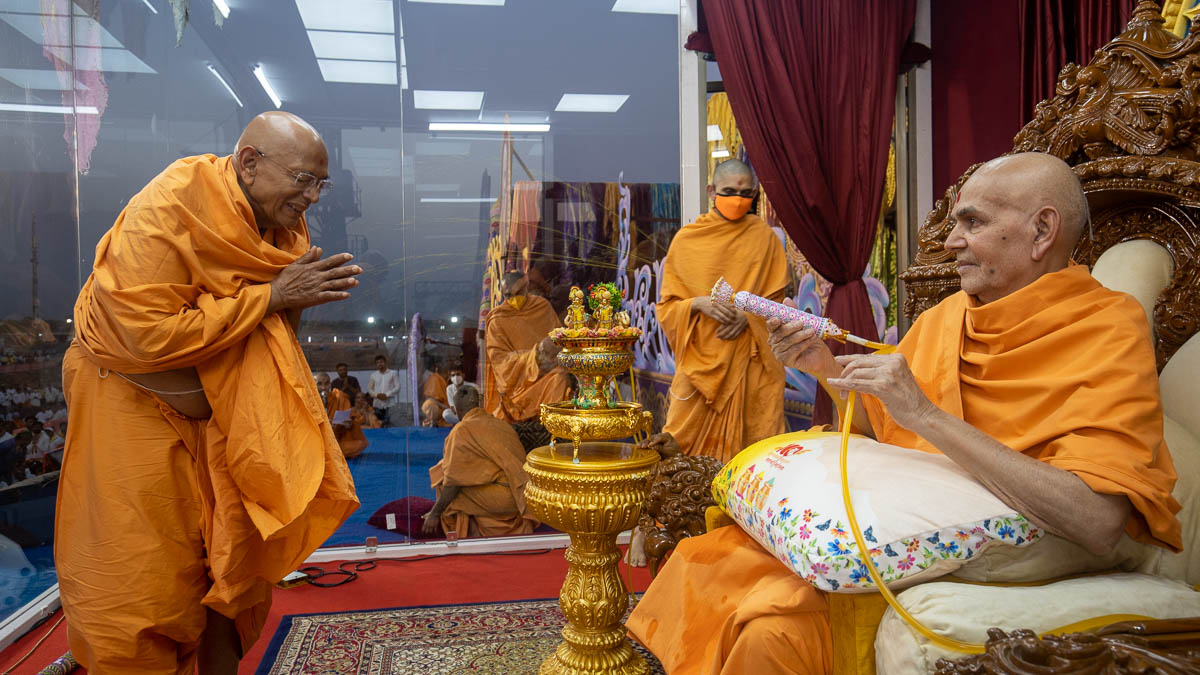 Swamishri sprays sanctified saffron-scented water on Pujya Tyagvallabh Swami