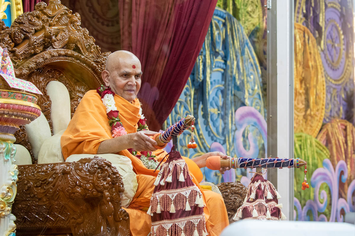 Swamishri sprays sanctified saffron-scented water on devotees and blesses them