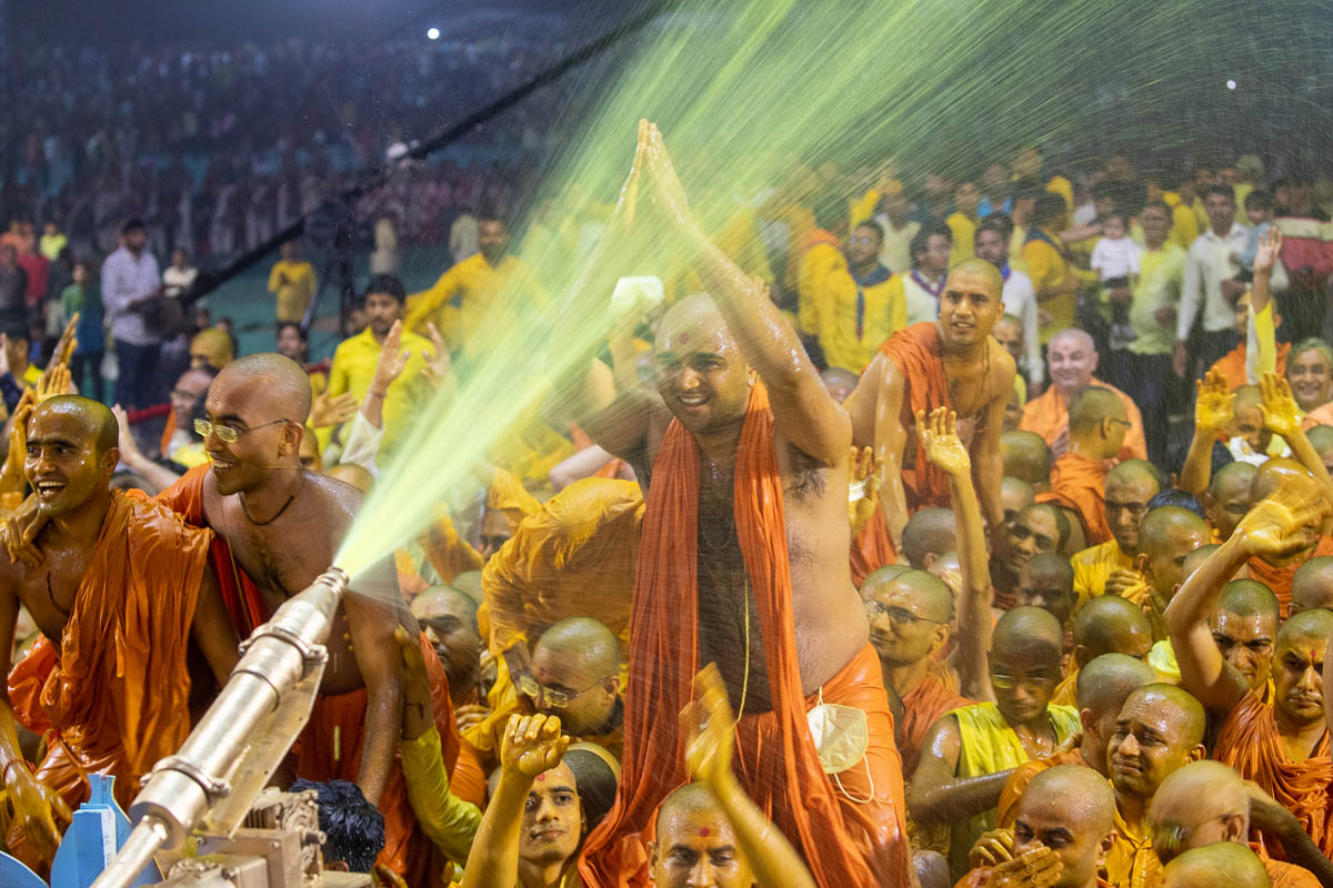 Swamishri sprays sanctified saffron-scented water on sadhus