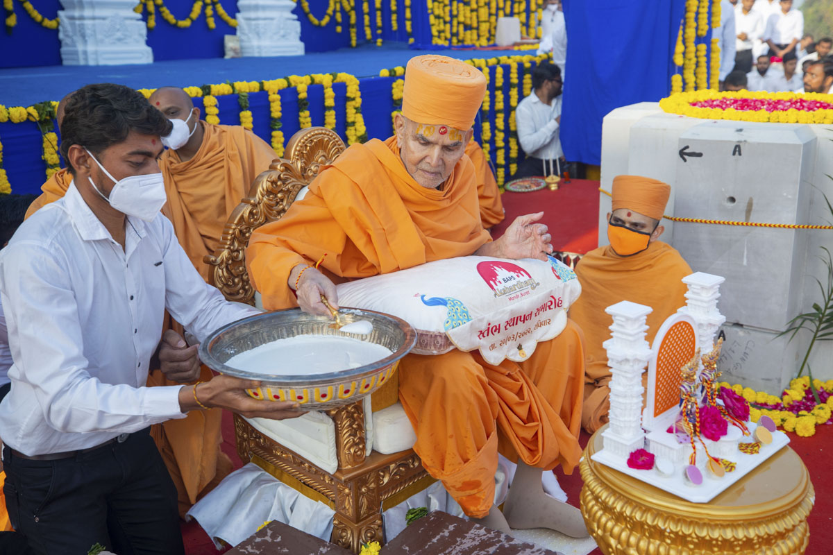Swamishri pours cement on the pillar base