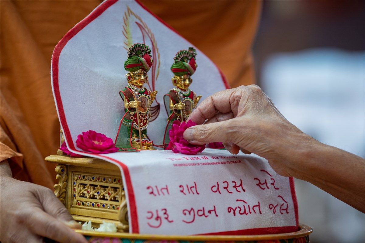 Swamishri offers a flower to Shri Harikrishna Maharaj and Shri Gunatitanand Swami