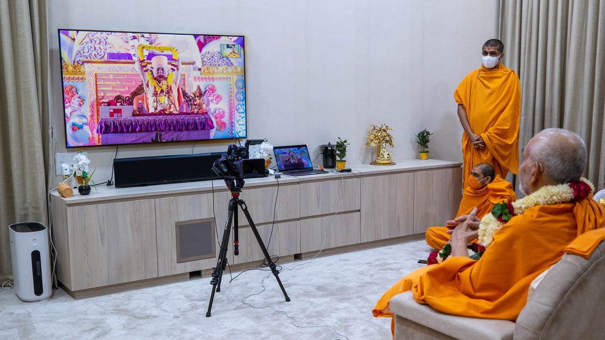 Pujya Viveksagar Swami honors Swamishri with a garland via video conference