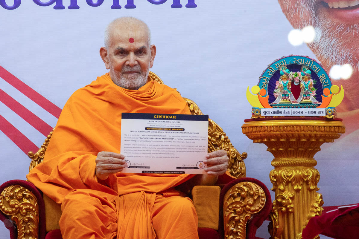 Swamishri displays a certificate for the youths