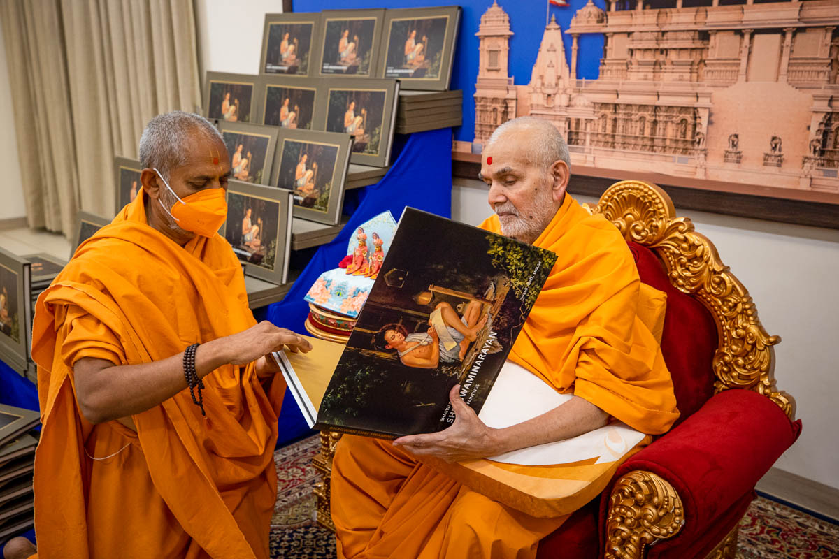 Swamishri observes a book: ‘Bhagwan Shri Swaminarayan: A Saga in Paintings’
