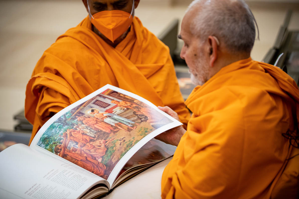 Swamishri observes a book