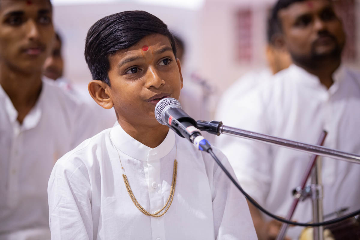 A child sings a kirtan in Swamishri's daily puja