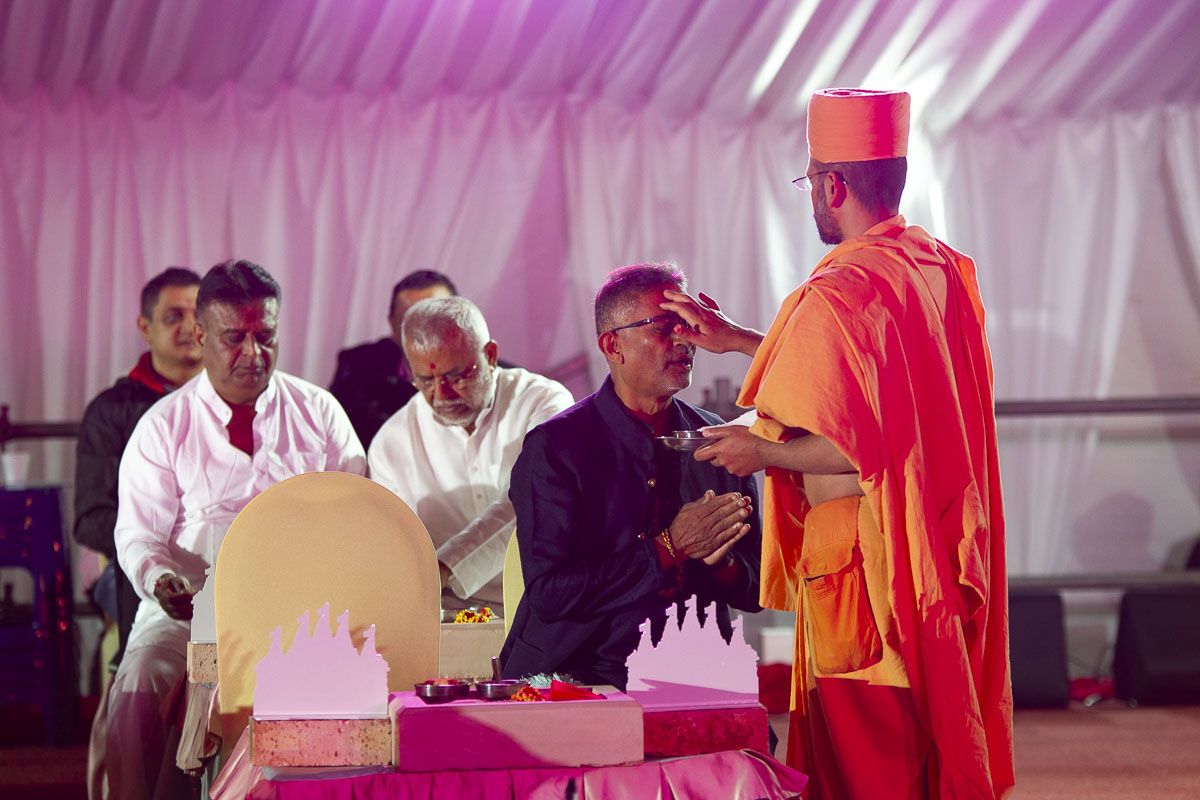 A sadhu applies chandlo to devotees and well-wishers