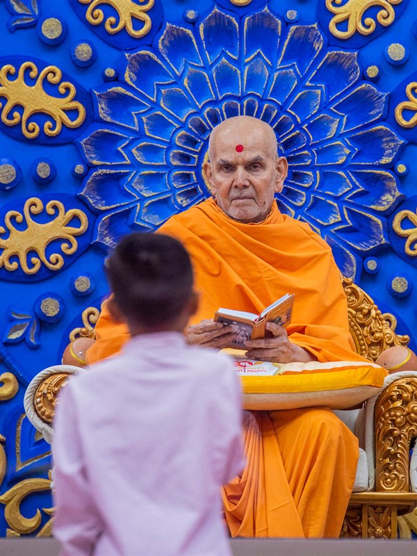 Swamishri blesses a child who recites scriptural passages in Swamishri's puja