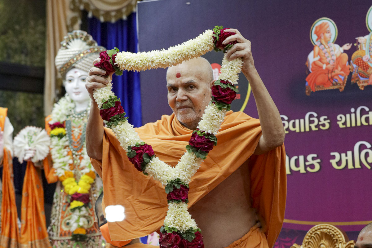 Swamishri honors Parivarik Shanti Abhiyan volunteers with a garland
