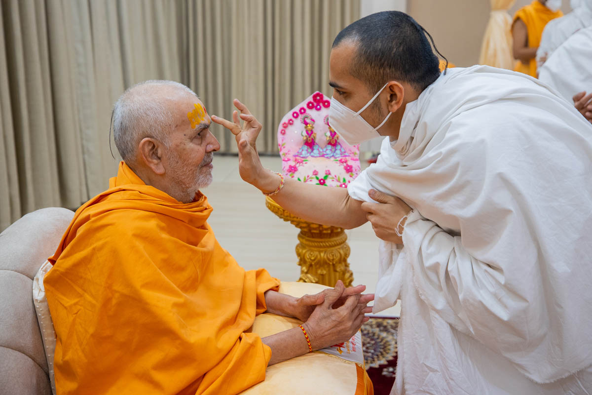 A parshad applies chandan archa to Swamishri