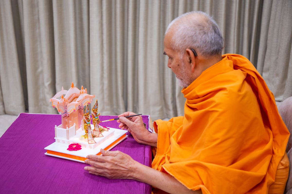 Swamishri applies finishing touches to chandan garments offered to Shri Harikrishna Maharaj and Shri Gunatitanand Swami