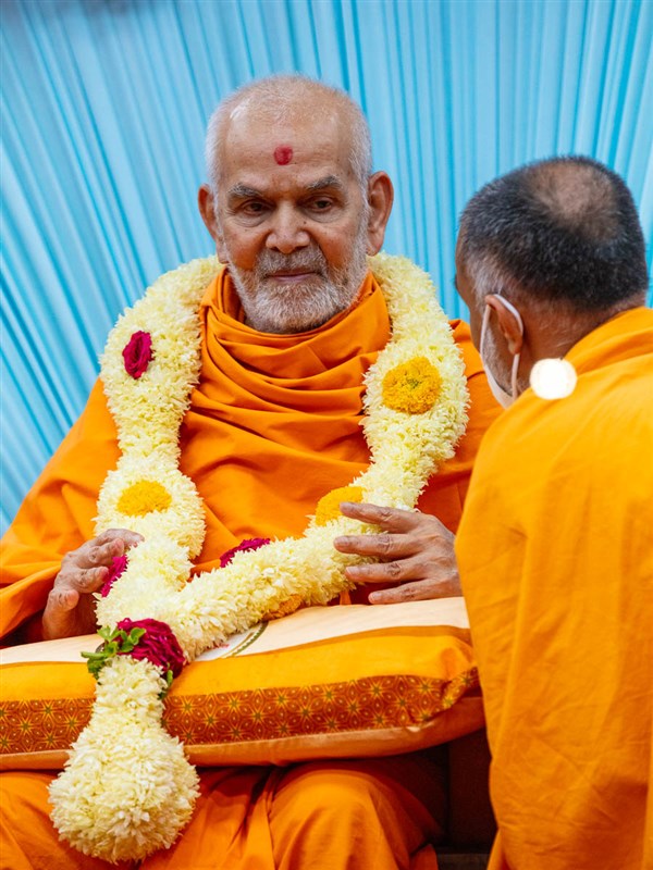 A sadhu honors Swamishri with a garland