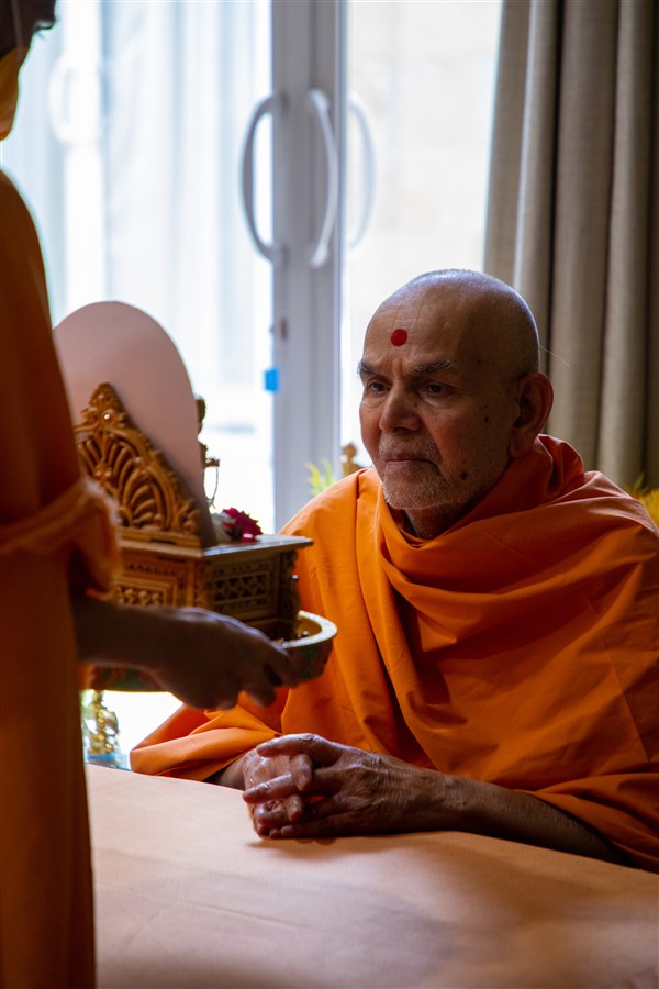 Swamishri observes chandan garments offered to Shri Harikrishna Maharaj and Shri Gunatitanand Swami 