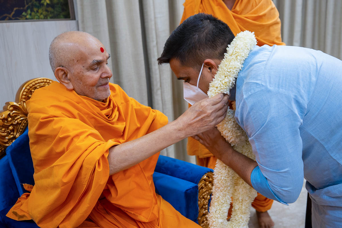 Swamishri honors Shri Harsh Sanghavi, Home Minister of Gujarat, with a garland
