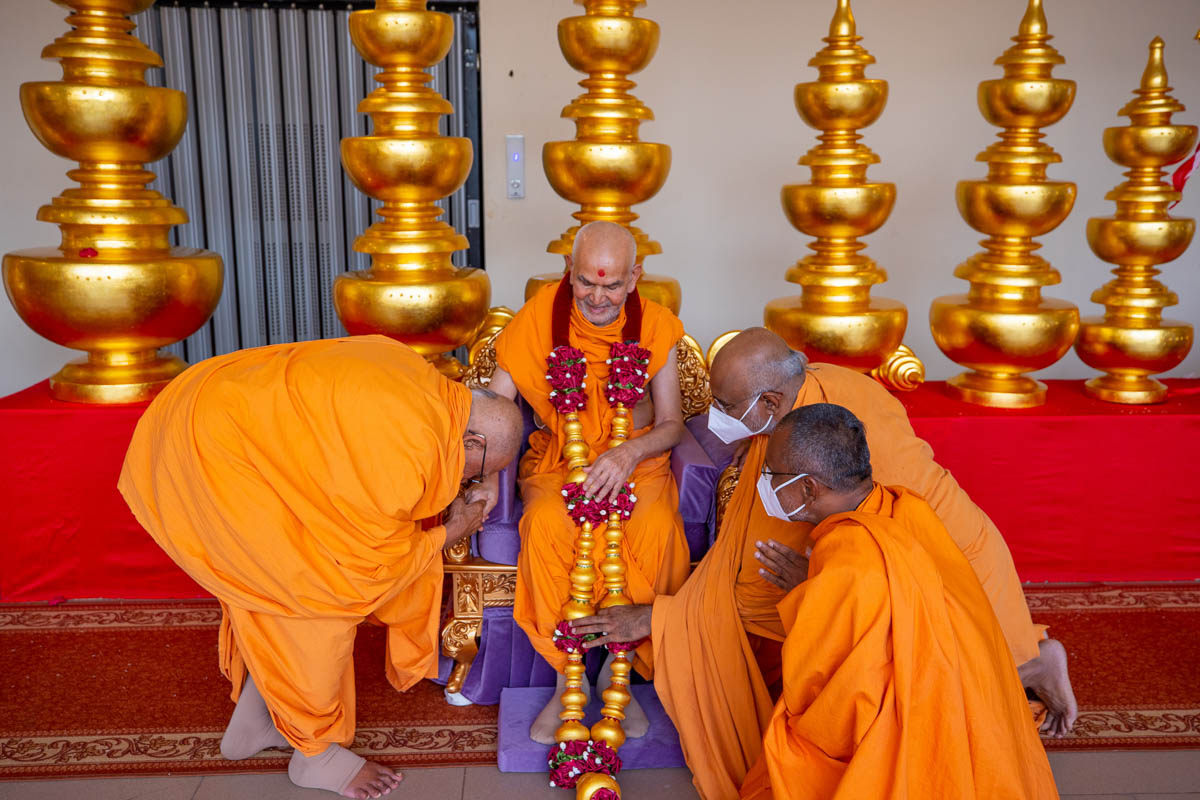 Pujya Kothari Swami and sadhus honor Swamisri with a garland