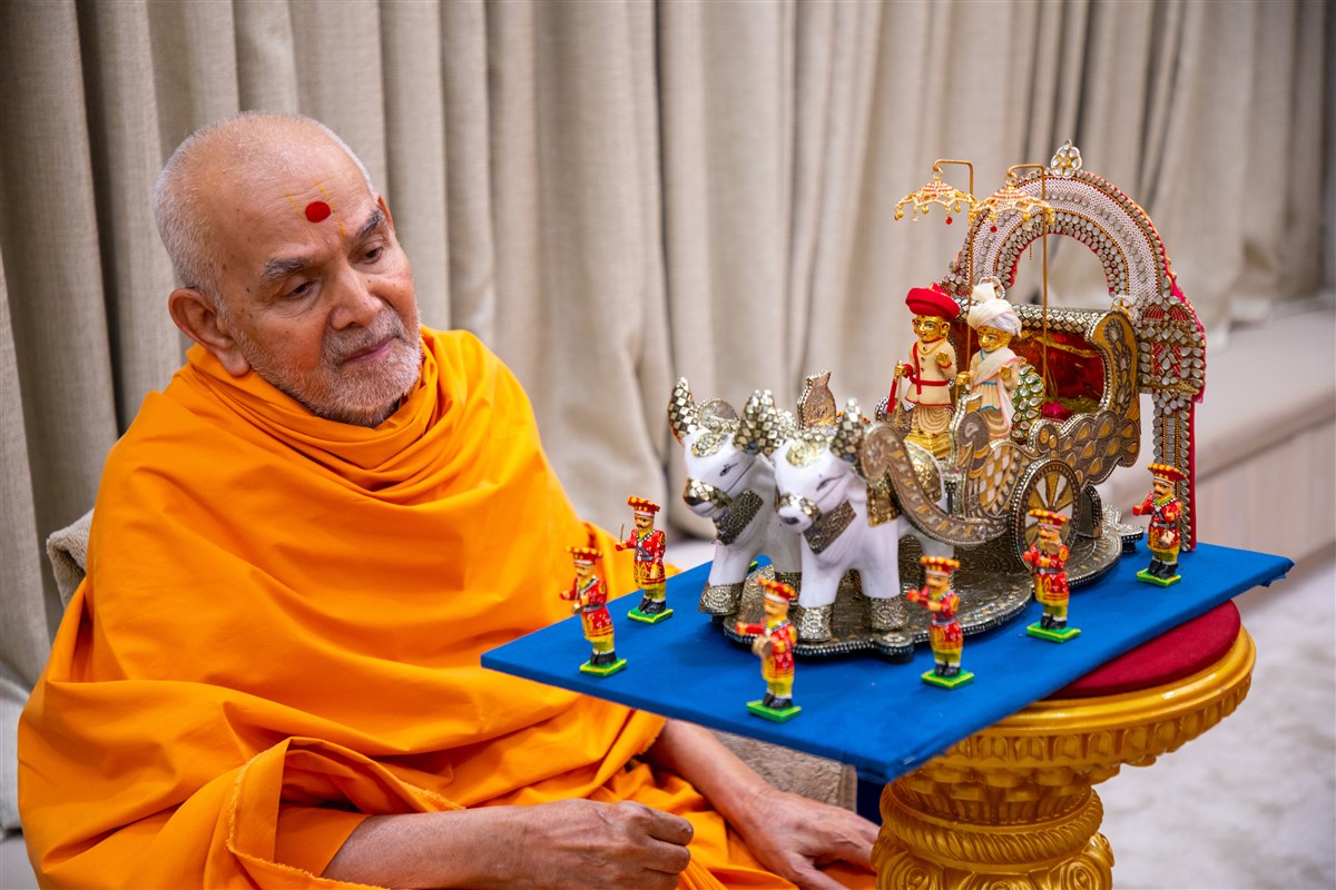 Swamishri observes chandan garments offered to Shri Harikrishna Maharaj and Shri Gunatitanand Swami 