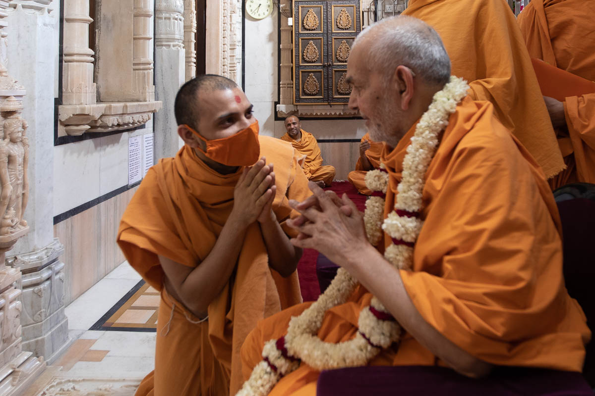 A sadhu welcomes Swamishri with a garland