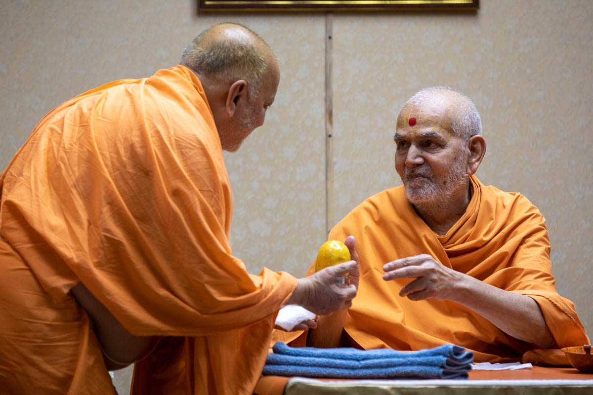 Swamishri gives prasad to Pujya Ishwarcharan Swami