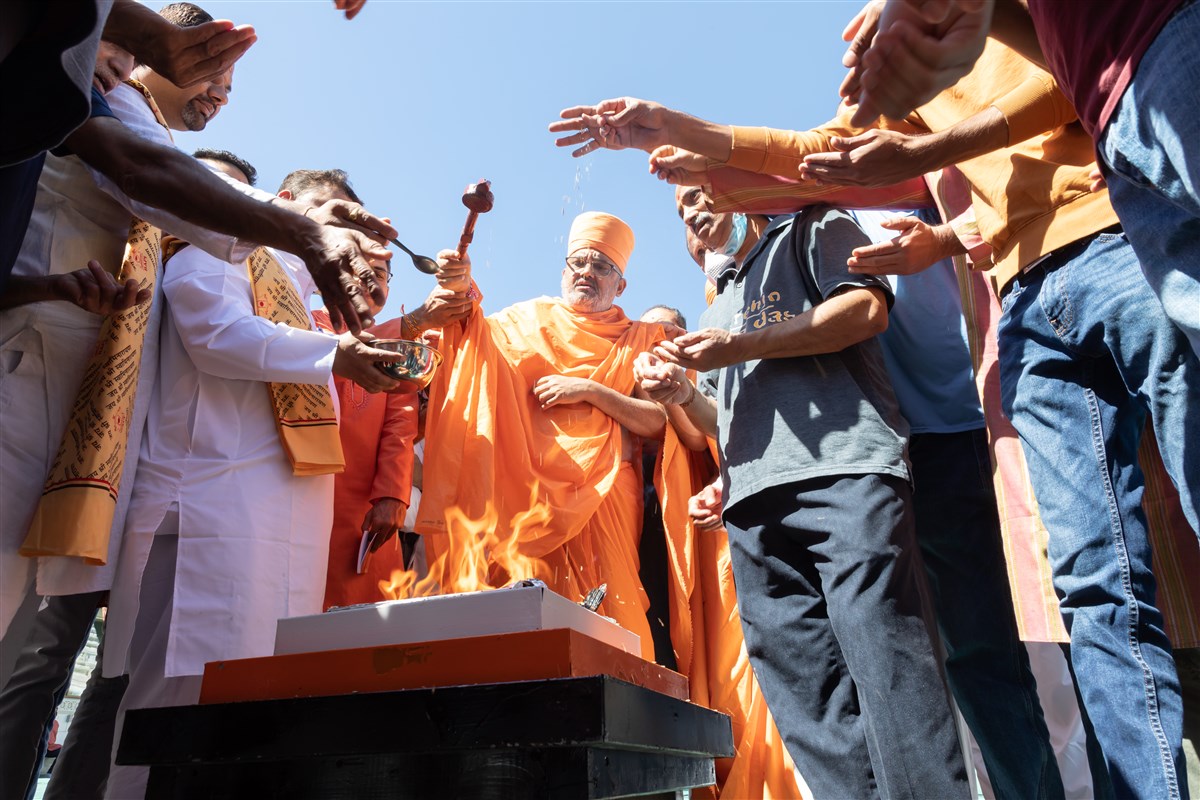 Ghee being offered into the sacred fire, using a traditional wooden yagna ladle
