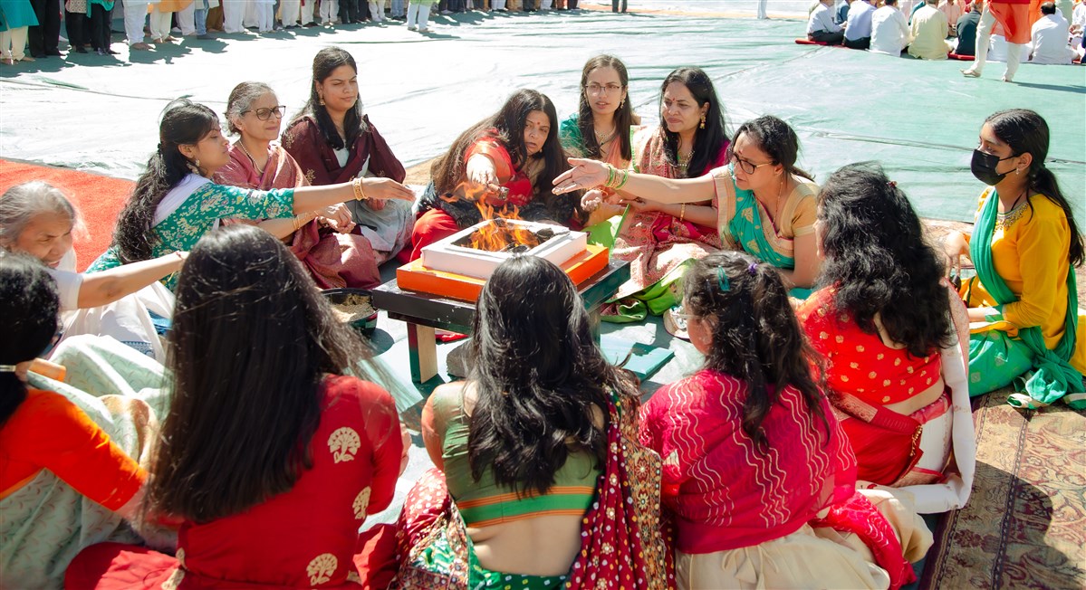Devotees participate in the yagna by offering sanctified grains in the sacrificial flame