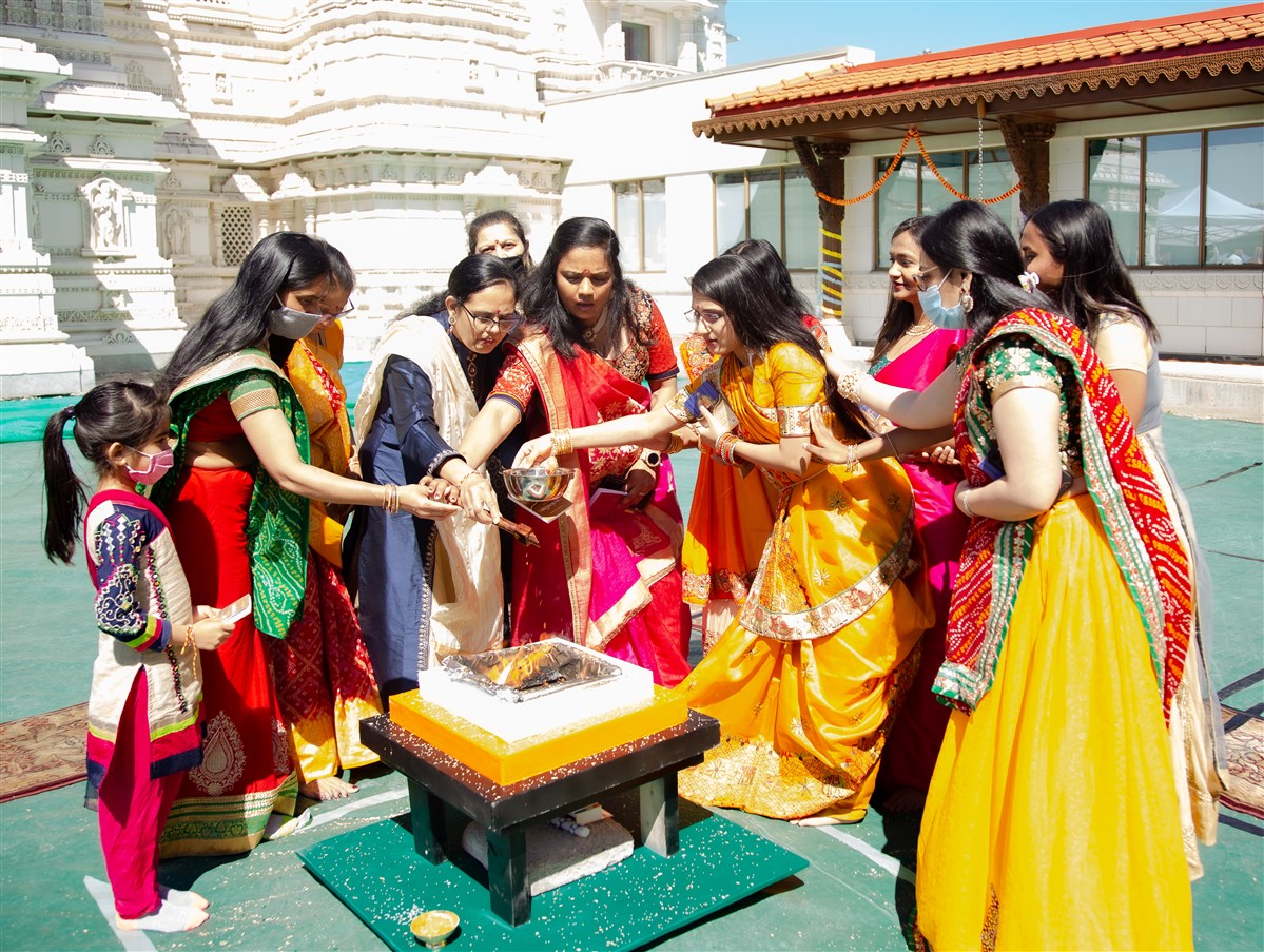 Devotees participate in the yagna by offering sanctified grains in the sacrificial flame
