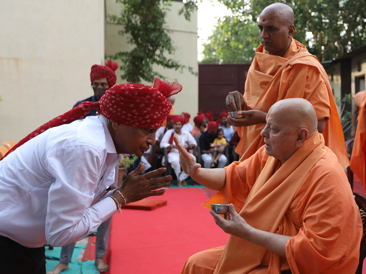 Pujya Ishwarcharan Swami applies a chandlo to Shri Trikambhai Patel