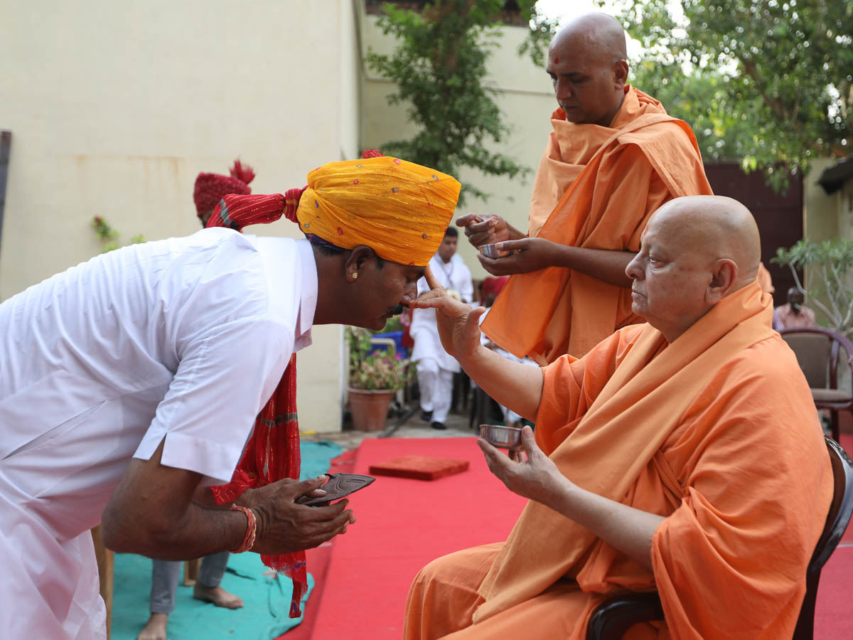 Pujya Ishwarcharan Swami applies a chandlo to Shri Ghanshyambhai Sompura