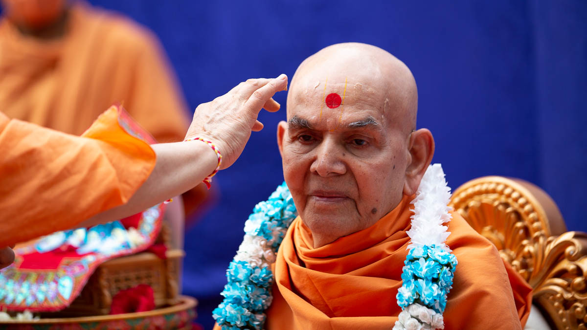Pujya Ishwarcharan Swami applies chandan archa to Swamishri