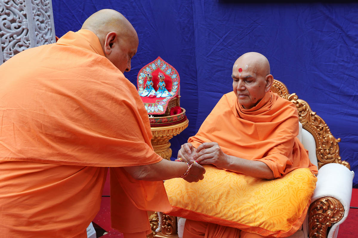 Swamishri ties a nadachhadi to Pujya Ishwarcharan Swami