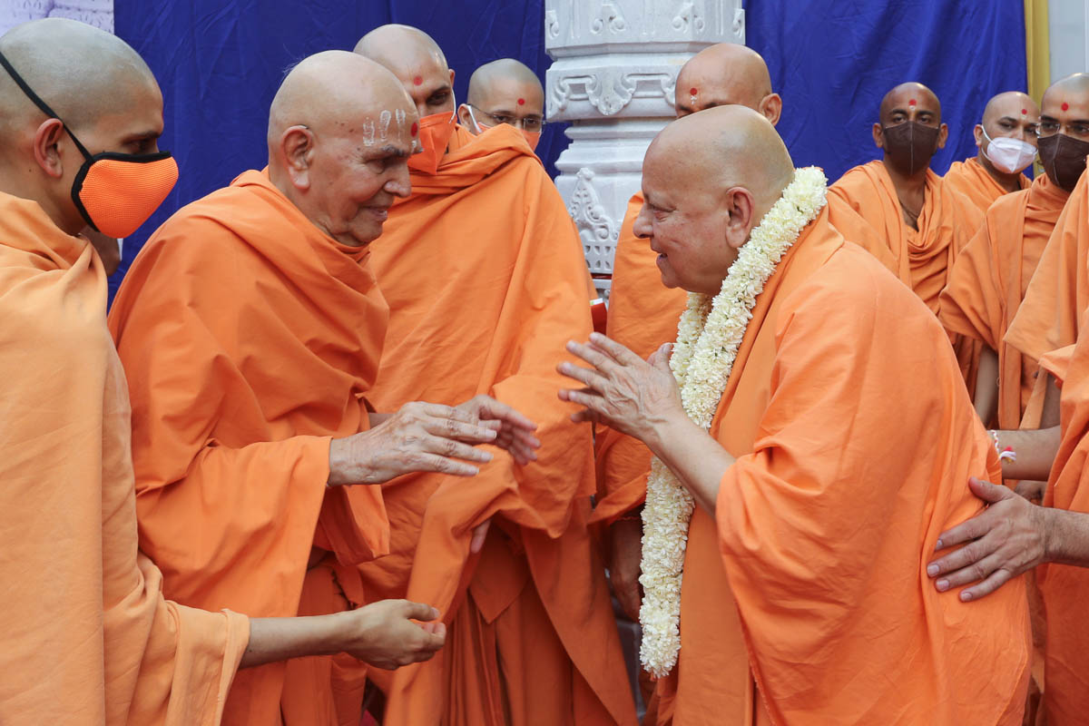 Swamishri honors Pujya Ishwarcharan Swami with a garland