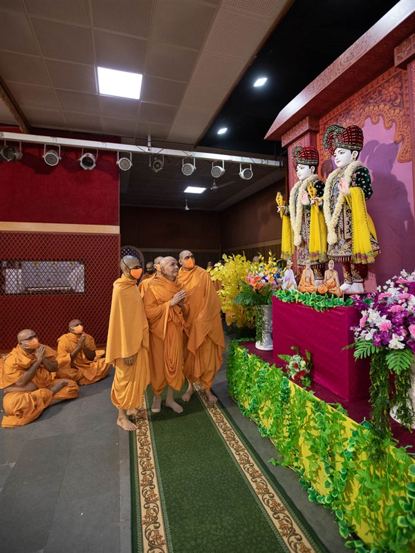 Swamishri engrossed in darshan of Bhagwan Swaminarayan, Aksharbrahma Gunatitanand Swami and Shri Guru Parampara