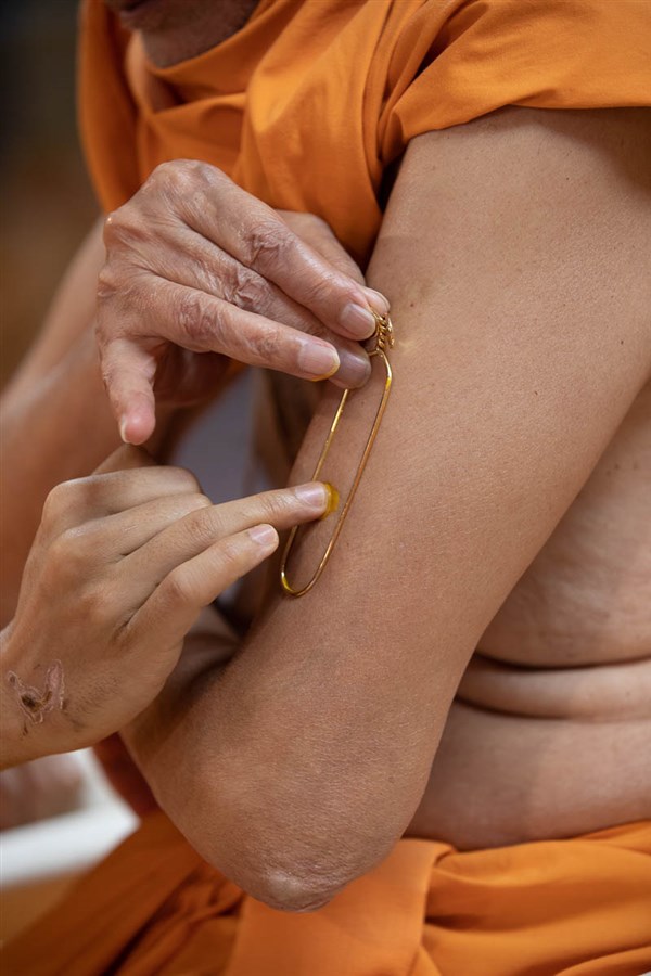 Swamishri applies a tilak on his upper arm during his morning puja