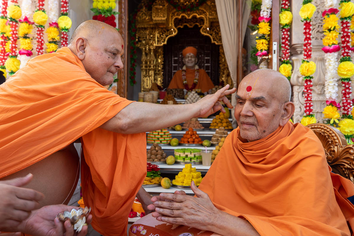 Pujya Ishwarcharan Swami applies chandan archa to Swamishri