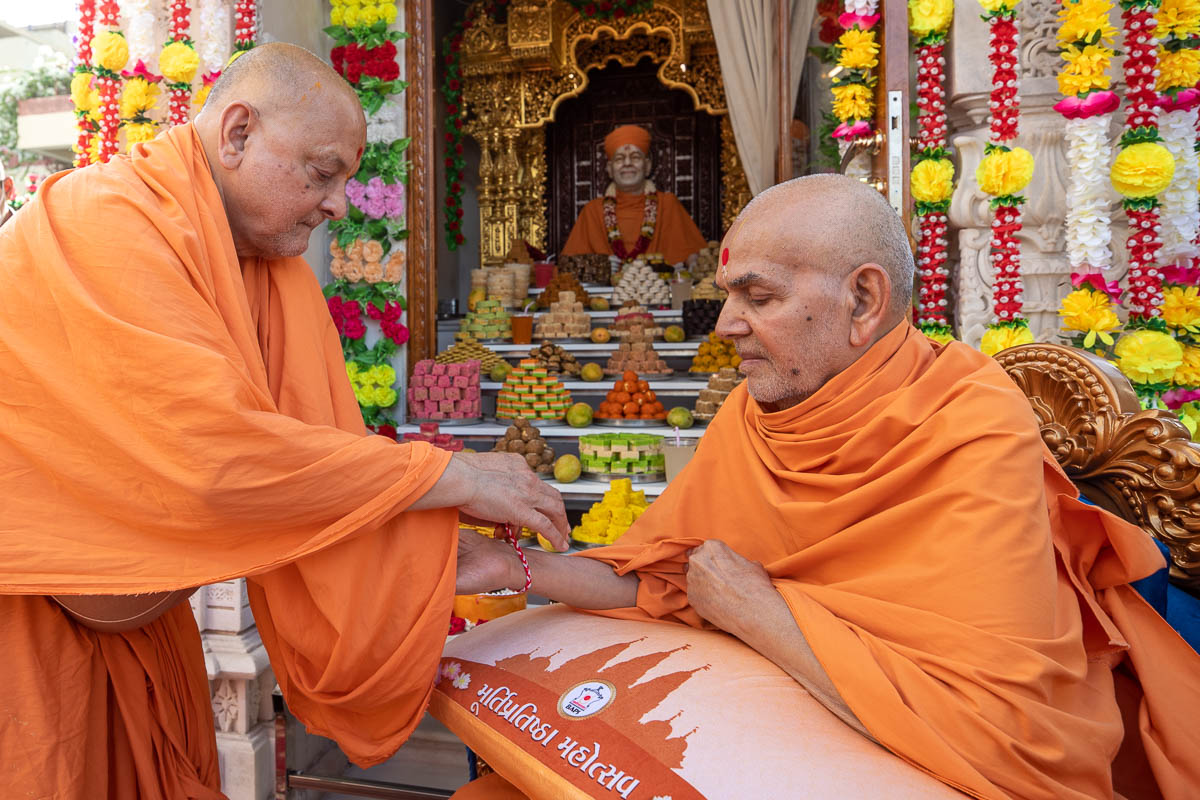 Pujya Ishwarcharan Swami ties a nadachhadi to Swamishri