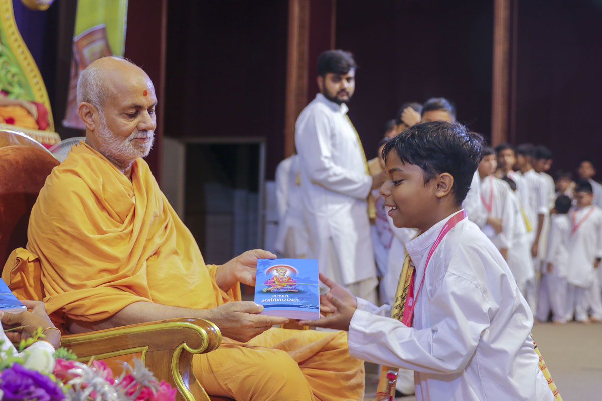 Pujya Viveksagar Swami gives a study book to a balak