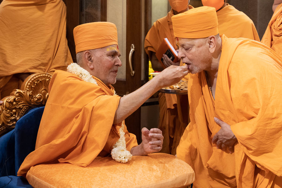 Swamishri offers prasad to Pujya Ishwarcharan Swami