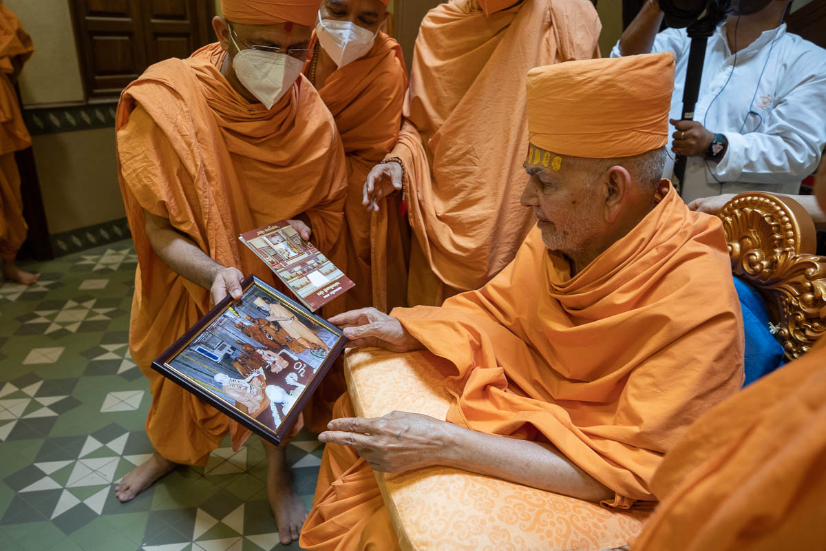 Swamishri observes a photo of Brahmaswarup Pramukh Swami Maharaj's visit to Yagnapurush Smruti Mandir in the year 2000