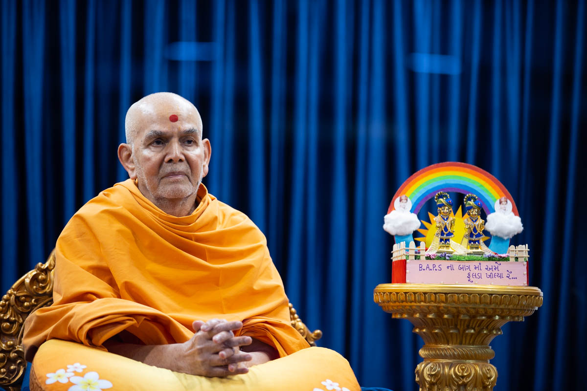 Swamishri greets all with folded hands in the Pramukh Swami Auditorium