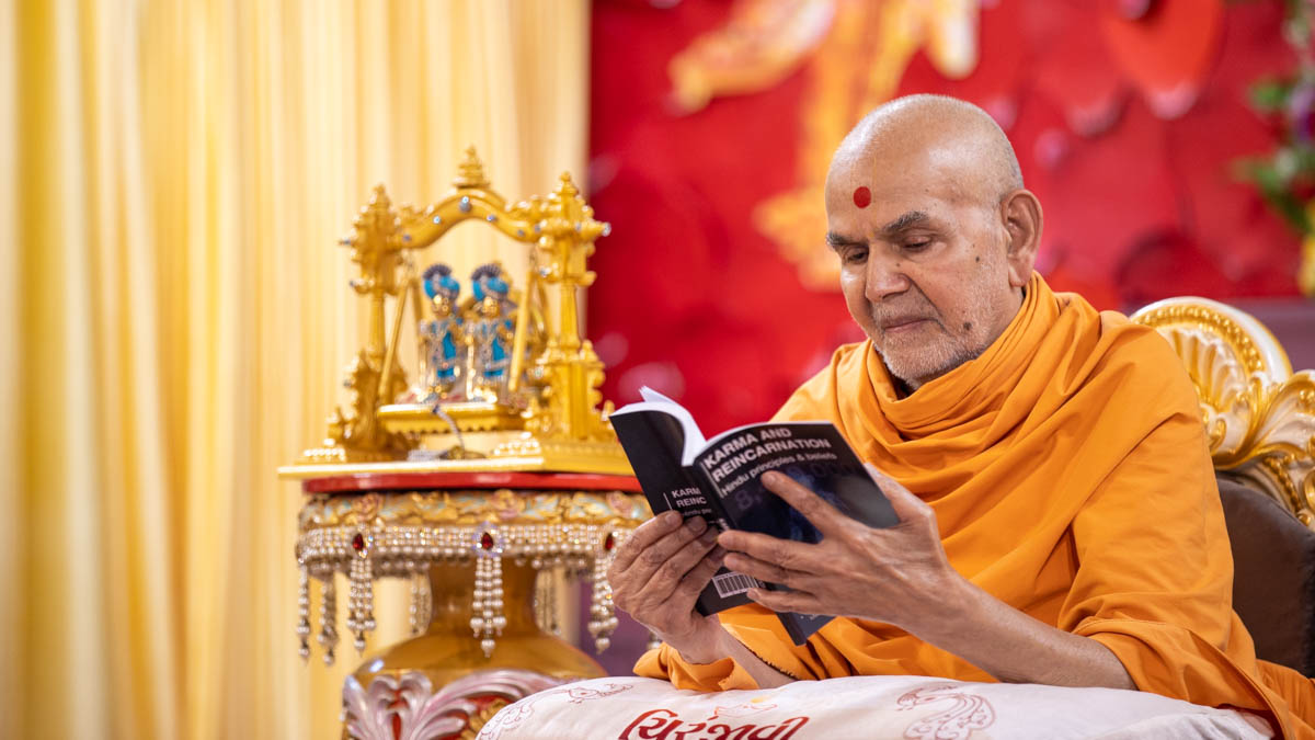 Swamishri sanctifies the 4th edition of the book 'Karma and Reincarnation: Hindu Principles & Beliefs'