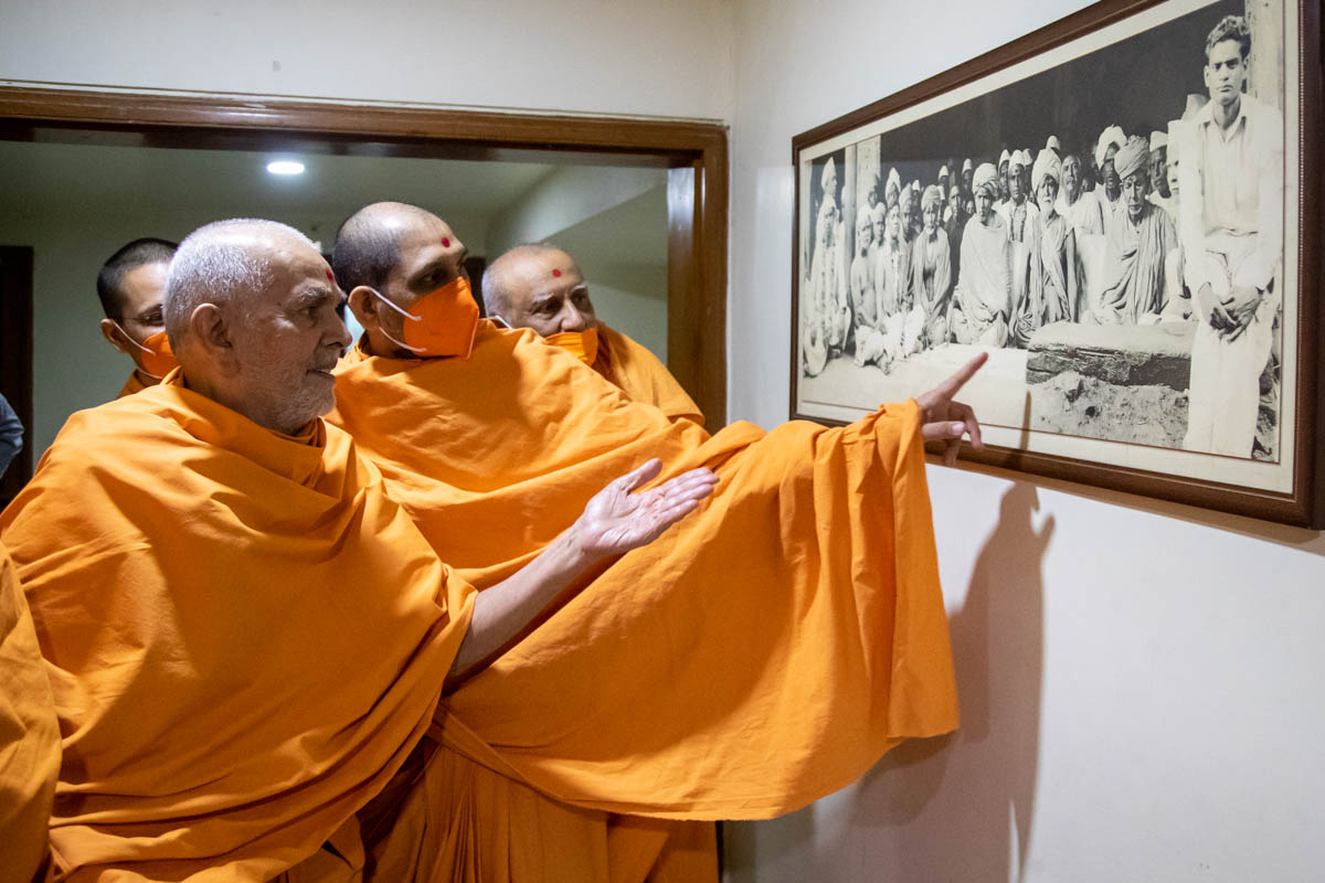Swamishri observes an old photo of Brahmaswarup Shastriji Maharaj