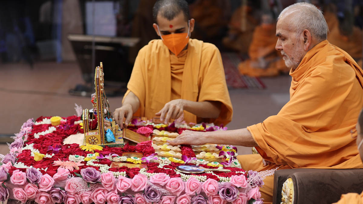 Swamishri adjusts the murtis during his daily puja