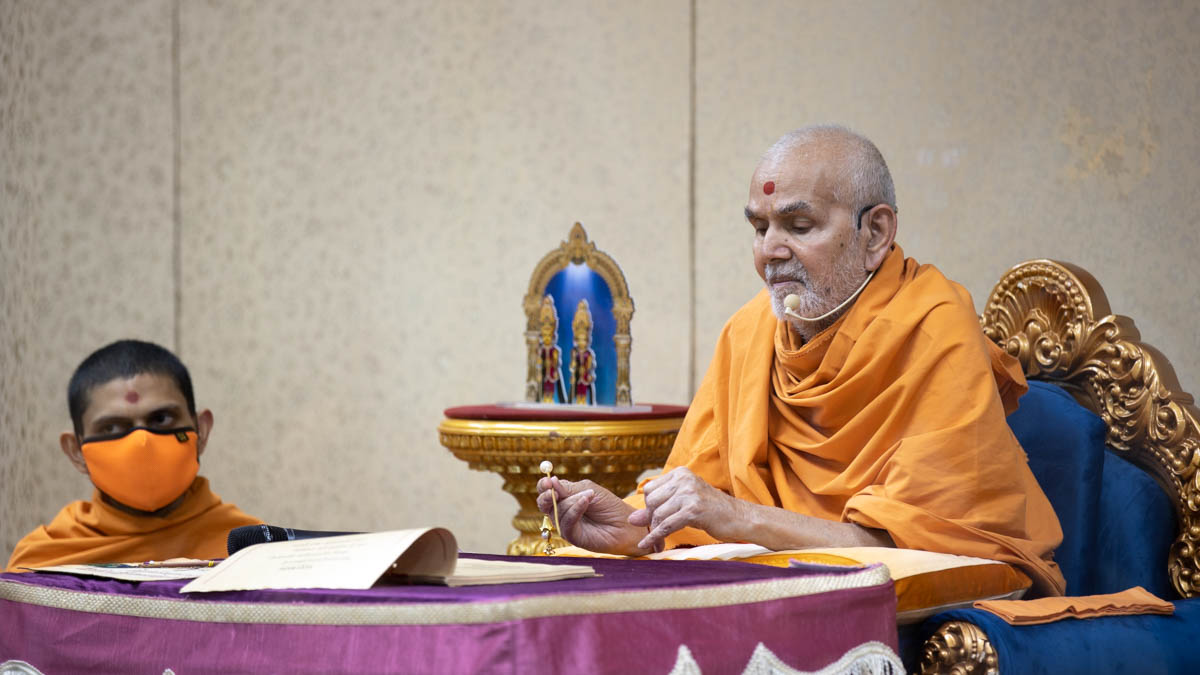 Swamishri selects a shlok for a student to recite