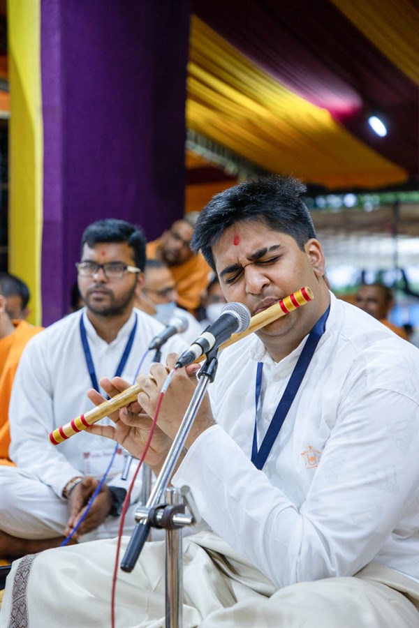 A youth plays a flute in Swamishri's daily puja